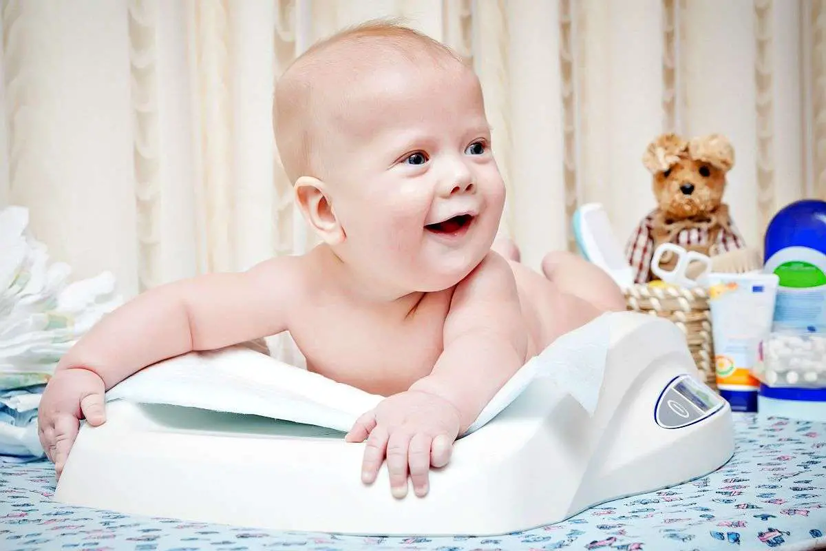 Happy baby lying in the scale | Baby Weight Chart | How Much Should My Baby Weigh? [INFOGRAPHIC]
