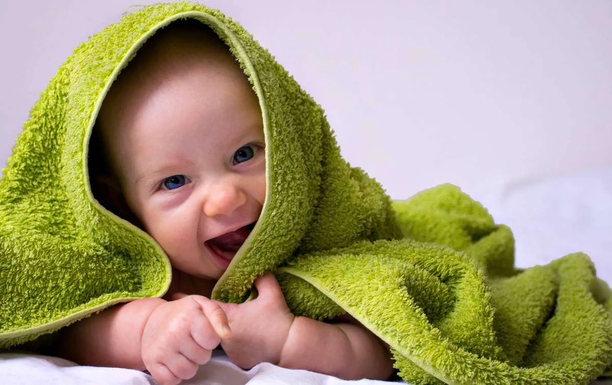 Happy, smiled half-year baby girl in a towel after bathing | Games Babies Love | Games For Babies To Keep Them Giggling