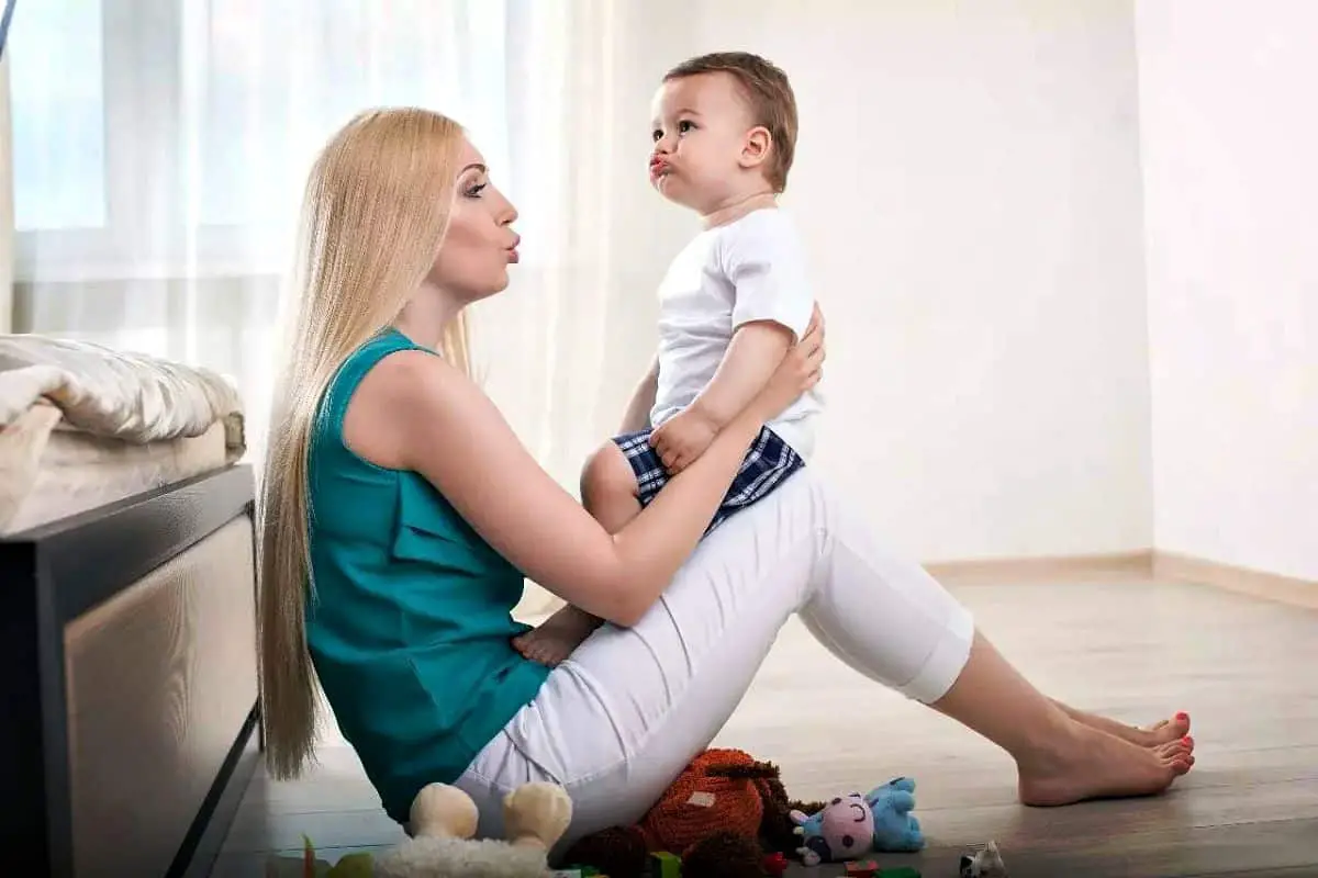 A mom is sitting on flooring and holding her little son | Breastfeeding 101: A Complete Guide To Feeding Your Baby